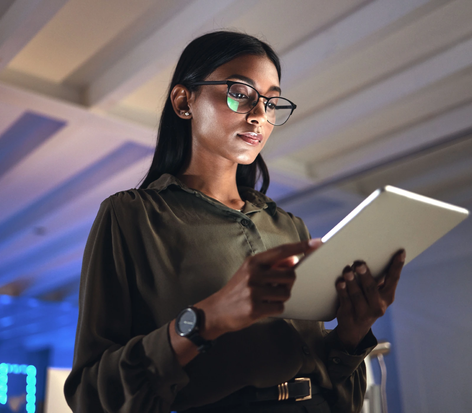 A woman in glasses is holding an ipad