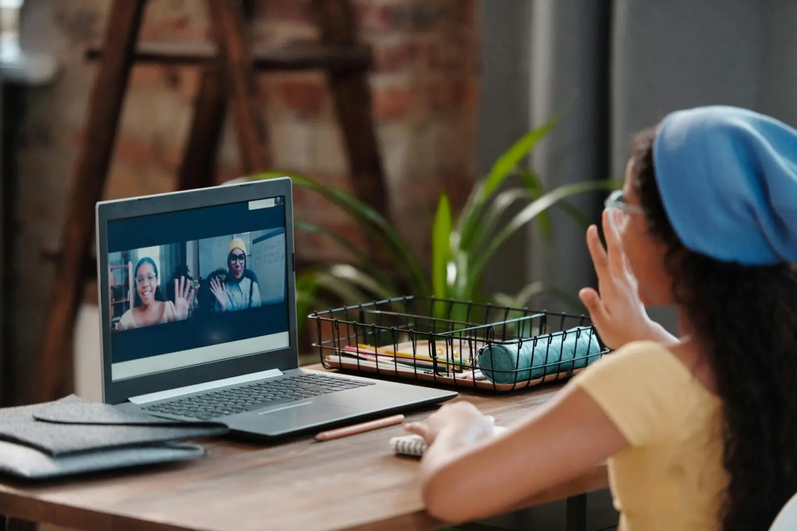 A child is sitting at a table with headphones on and looking at a laptop.